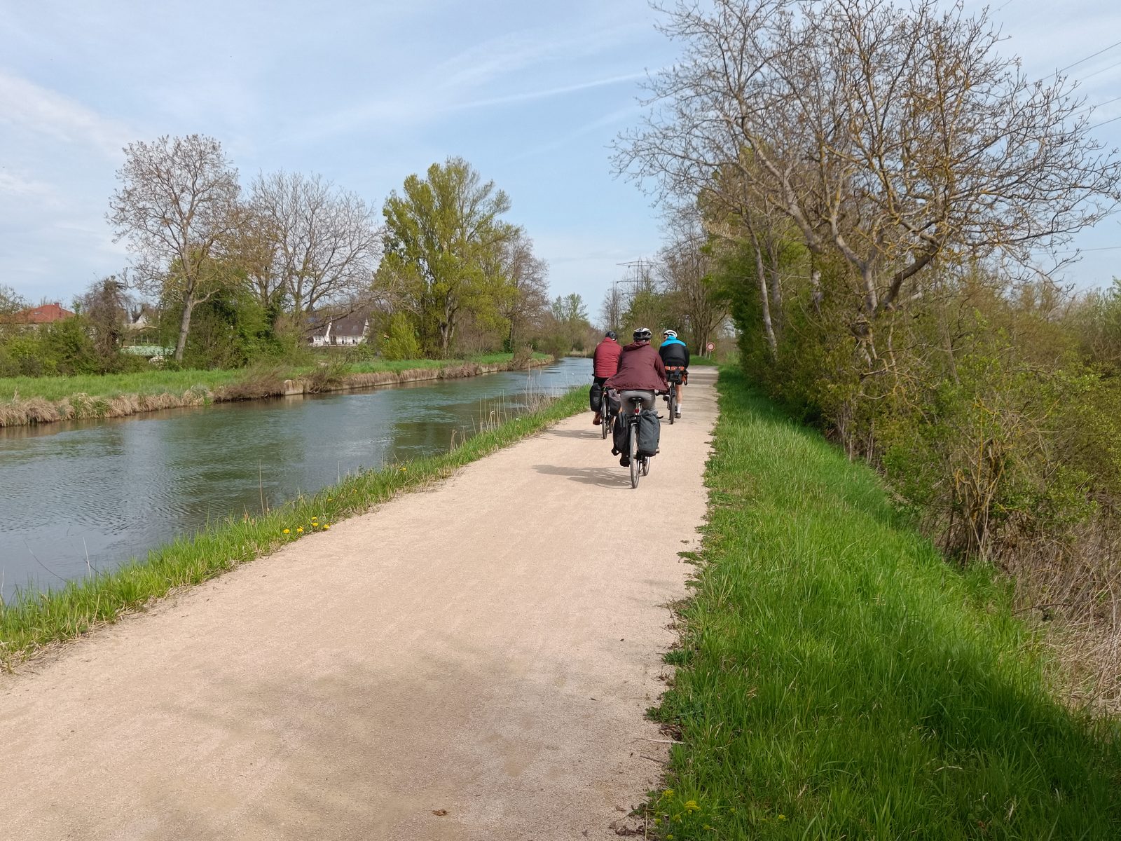 Trois cyclotouristes avec sacoches sur la piste cyclable longeant le canal de Kembs